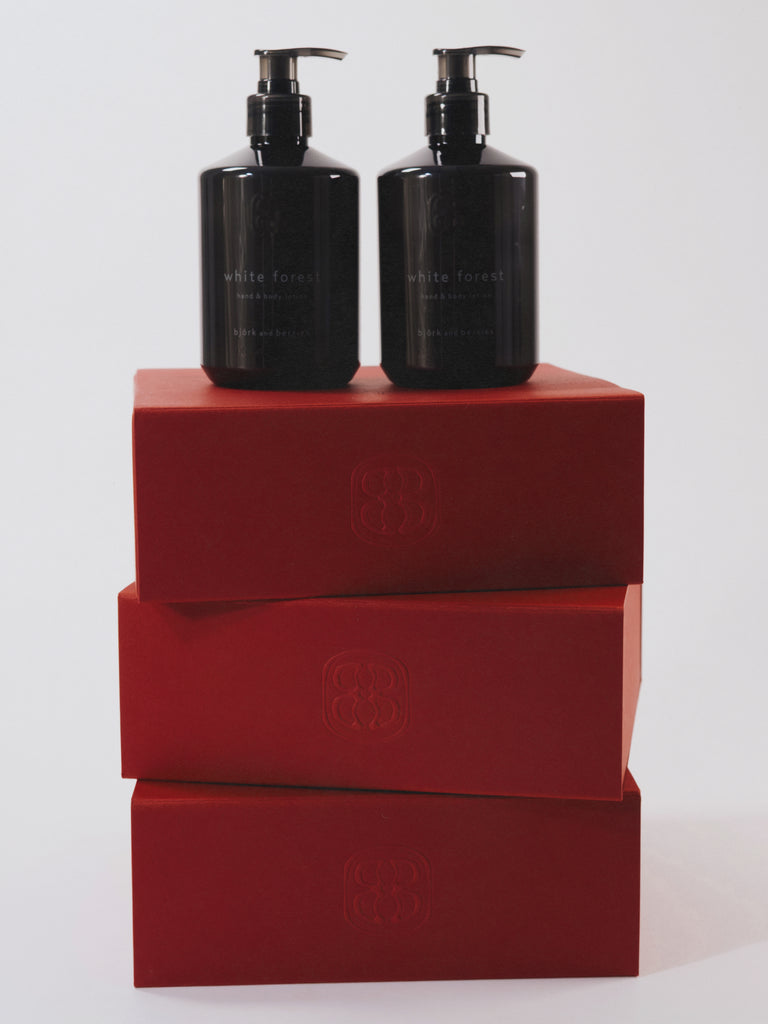 Two black bottles with pump dispensers on red boxes against a white background
